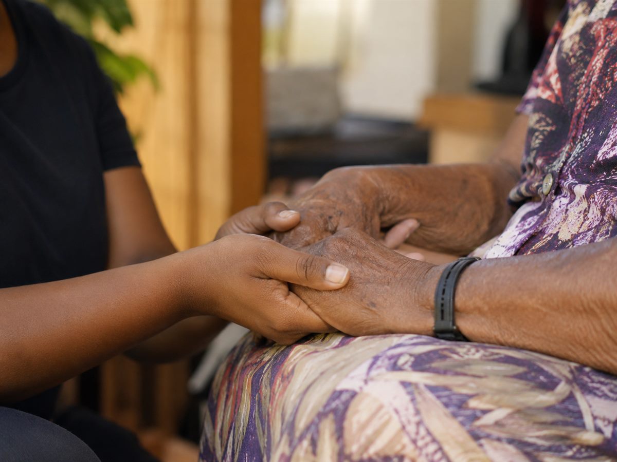 A Glory Care support worker gently holding the hands of an older person